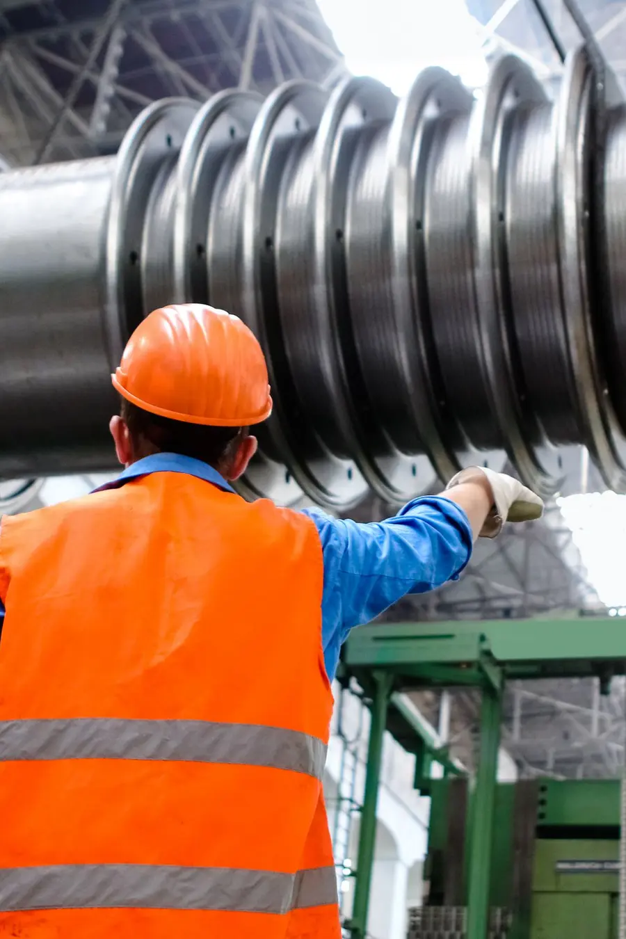 Worker in protective equipment inspecting a turbine rotor in a plant hall